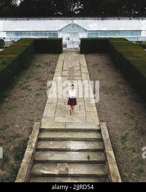 Giovane donna in piedi di fronte a un padiglione di vetro a Temple Newsam, foto drone, Leeds, Inghilterra, Regno Unito Foto Stock