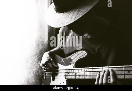 Come scala di grigi estetica di un maschio che tiene un accordo sulla chitarra basso Foto Stock