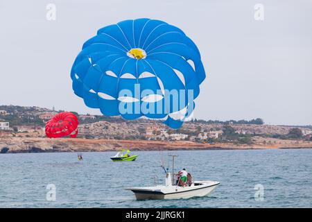 Ayia Napa, Cipro - 16 giugno 2018: I turisti sono in motoscafo parasailing. Baia di Agia Napa, Cipro Foto Stock