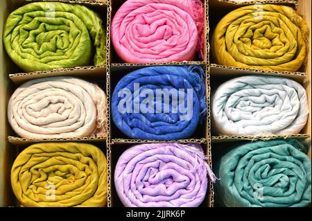 A closeup shot of various colors of ethnic silk pashmina scarves in boxes Foto Stock