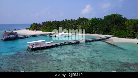 An Aerial shot of a paradise island with tropical trees and villas surrounded by turquoise water Foto Stock