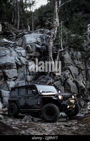 Un colpo verticale di una Jeep Wrangler nera fuori strada nelle colline rocciose di Riverside, Stati Uniti Foto Stock