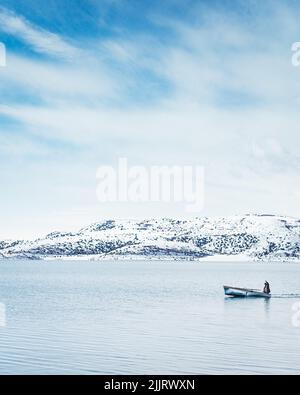 Una verticale di un pescatore che naviga su una barca nel lago Sevan, Armenia Foto Stock