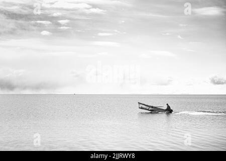 Una scala di grigi di un pescatore che naviga sulla barca nel lago Sevan , Armenia Foto Stock