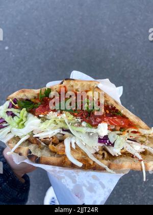 Un fuoco selettivo di una mano che tiene un pasto kebab doner Foto Stock