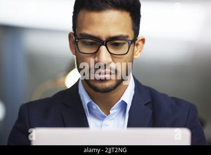 Vista frontale di un uomo d'affari concentrato che utilizza un laptop, trading sul mercato azionario. Operatore serio indossare occhiali e lavorare online con un computer Foto Stock