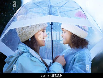 Pronta ad avere un po' di divertimento. Una giovane donna attraente che si lega con la figlia fuori sotto la pioggia. Foto Stock