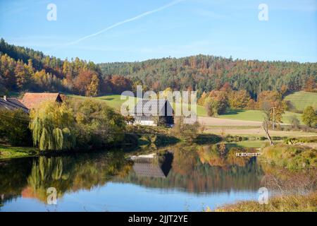 Una vista aerea di piccole case vicino al lago circondato da alberi autunnali Foto Stock