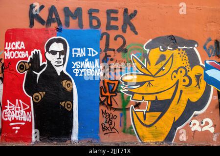 Un'immagine di dipinti di Street art dai colori vivaci su una parete arancione con facce di carattere Foto Stock