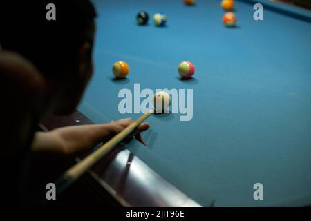 Giocatore di biliardo che colpisce il cue ball, vista sulla spalla Foto Stock