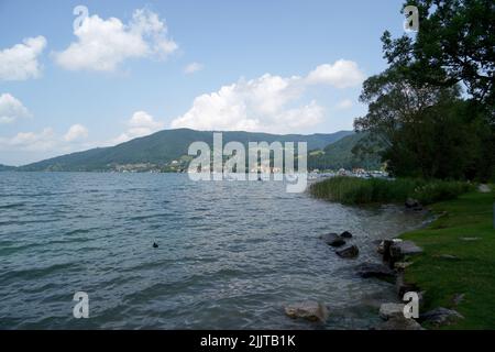 Una vista panoramica di un lago contro alberi verdi e montagne sulla riva Foto Stock