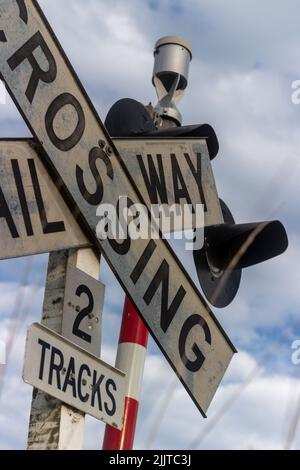 Un colpo verticale di un cartello Railroad Crossing con sfondo cielo nuvoloso Foto Stock