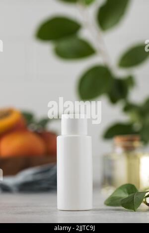 Mockup di un tubo bianco di cosmetici con estratto di nocciolo di albicocca tra le foglie. Cosmetici vegetali naturali. Layout. Foto Stock