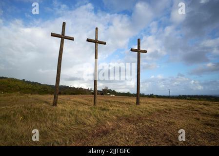 Un angolo basso di tre croci di legno nel campo contro il cielo blu sfondo Foto Stock