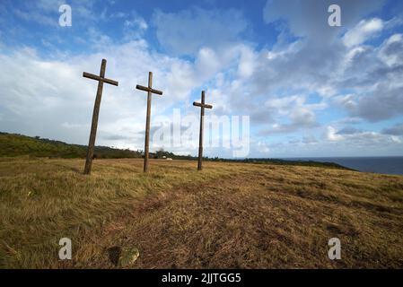 Un angolo basso di tre croci di legno nel campo contro il cielo blu sfondo Foto Stock
