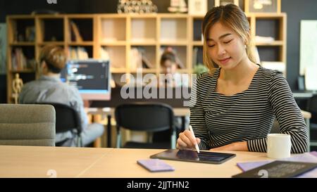 Giovani programmatori o sviluppatori di software che utilizzano tablet digitali, lavorando in un ufficio moderno Foto Stock