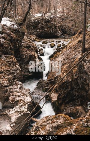 Un colpo verticale di un ruscello che scende attraverso rocce e scogliere in un canyon Foto Stock