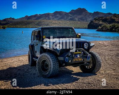 Una Jeep Wrangler nero off-roading su Arizona sentieri vicino a un lago Foto Stock