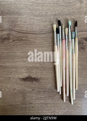 A set of different paint brushes on a wooden table Foto Stock