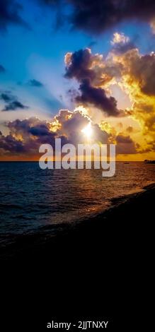 Scena drammatica di cielo nuvoloso vibrante sul mare tranquillo al tramonto Foto Stock