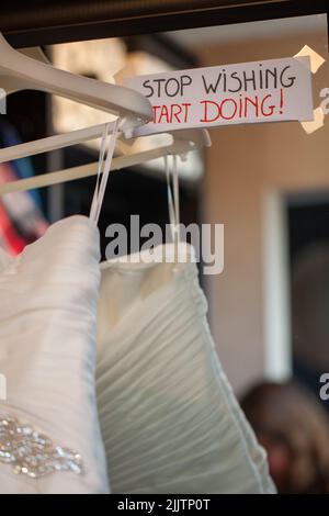 Citazione di amore su uno specchio accanto al vestito di nozze a matrimonio, la citazione dice smettere di desiderare, iniziare a fare. Foto di alta qualità Foto Stock