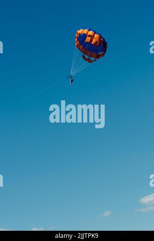 Un colpo verticale di turisti che si godono parasailing in Algarve, Portogallo Foto Stock