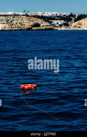 A vertical shot of a red lifebuoy on a bay of Algarve, Portugal Stock Photo