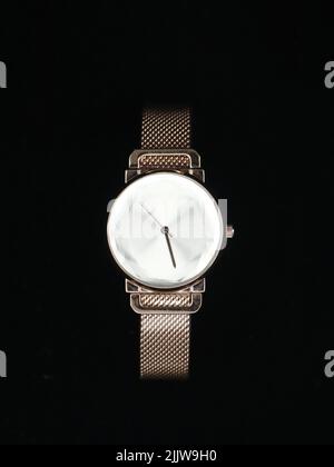 un lussuoso orologio analogico da donna in oro rosa con quadrante bianco isolato su sfondo nero Foto Stock