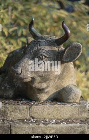 Statua in pietra buddista di un toro che giace con monete collocate come offerta nel tempio di Enryaku del monaco di Ryogen nella montagna di Hiei vicino a Kyoto, Giappone. Foto Stock