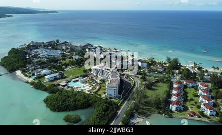 Un'antenna di hotel su una spiaggia coperta di verde contro un mare turchese a Montego Bay, Giamaica Foto Stock