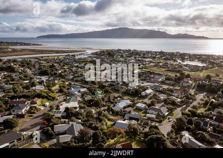 Waikanae Beach e Kapiti Island dall'estuario del fiume alla casa della vecchia spiaggia. Pomeriggio nuvoloso con il sole tardivo che provoca il flare delle lenti Foto Stock