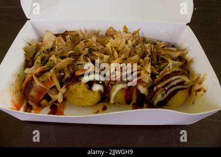 Takoyaki è cibo Giappone, sotto forma di piccole palle di farina di pasta farcita con pezzi di polpo. cibo giapponese, isolato su sfondo di legno Foto Stock