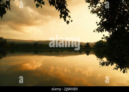Tramonto d'oro sul lago vicino a Wernigerode, sui monti Harz. Riflesso delle nuvole nell'acqua Foto Stock