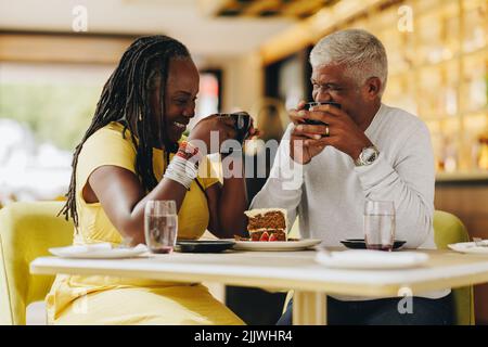 Una coppia allegra che ride insieme mentre si fa un caffè in un bar. Spensierate la coppia anziana che si è recata bene in un ristorante. Coppia matura felice Foto Stock