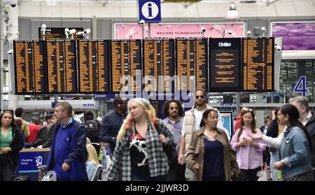 Passeggeri ferroviari e un punto di informazione sull'orario dei treni presso la stazione ferroviaria di Piccadilly, Manchester, Greater Manchester, Inghilterra, Regno Unito, Isole britanniche. Il sindacato Aslef ha dichiarato oggi che i macchinisti di nove compagnie ferroviarie sciopereranno per altre 24 ore il 13th agosto 2022, oltre la retribuzione. Aslef dice che le aziende non sono riuscite a fare un'offerta salariale per aiutare i membri a tenere il passo con gli aumenti del costo della vita. Foto Stock