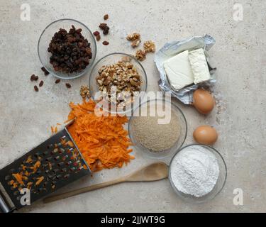vista ad angolo elevato degli ingredienti in ciotole di vetro per preparare la torta di carota su tavola di pietra con carota grattugiata Foto Stock