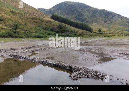 Haweswater, Cumbria, Inghilterra, luglio 28th 2022. Le rovine di Mardale Green, un villaggio un tempo affondato in Cumbria sono emerse dalle profondità mentre i livelli dell'acqua continuano a scendere in Inghilterra. Haweswater Reservoir fornisce acqua potabile ai residenti di Manchester. Nonostante una piccola quantità di precipitazioni sulle campane del Cumbria, i livelli dell'acqua sono ancora ben al di sotto delle altezze normali su quello che è stato coniato "il luglio più secco dal 1911". Questo ha rivelato vecchie strade, mura e persino un ponte pedonale in pietra. PIC by Credit: Michael Scott/Alamy Live News Foto Stock