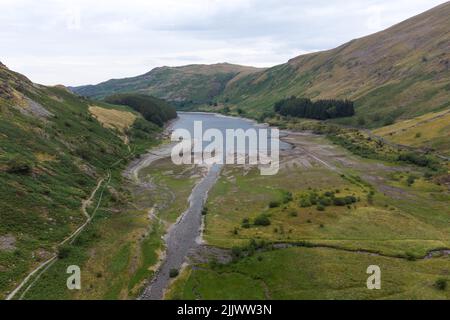 Haweswater, Cumbria, Inghilterra, luglio 28th 2022. Le rovine di Mardale Green, un villaggio un tempo affondato in Cumbria sono emerse dalle profondità mentre i livelli dell'acqua continuano a scendere in Inghilterra. Haweswater Reservoir fornisce acqua potabile ai residenti di Manchester. Nonostante una piccola quantità di precipitazioni sulle campane del Cumbria, i livelli dell'acqua sono ancora ben al di sotto delle altezze normali su quello che è stato coniato "il luglio più secco dal 1911". Questo ha rivelato vecchie strade, mura e persino un ponte pedonale in pietra. PIC by Credit: Michael Scott/Alamy Live News Foto Stock