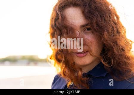 Giovane donna che guarda la macchina fotografica contro il cielo Foto Stock