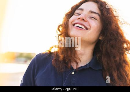 Felice giovane donna con gli occhi chiusi contro il cielo Foto Stock