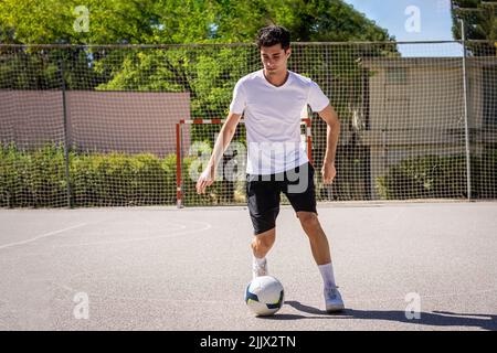 Corpo pieno di giovane uomo che gioca a calcio in campo Foto Stock