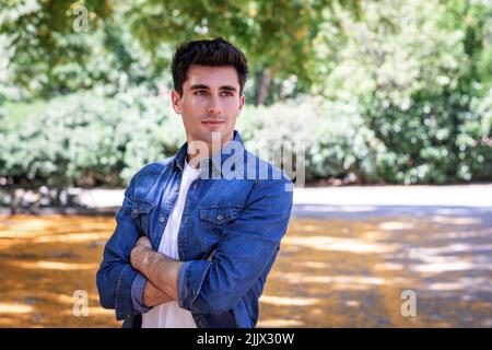 Primo piano ritratto di sorridente giovane uomo con giacca in denim guardando lontano Foto Stock
