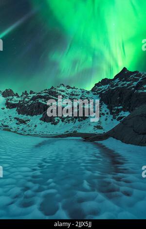 Scenario di scogliere rocciose con cime innevate sotto le luminose luci aurora borealis nel lago Agvatnet Foto Stock