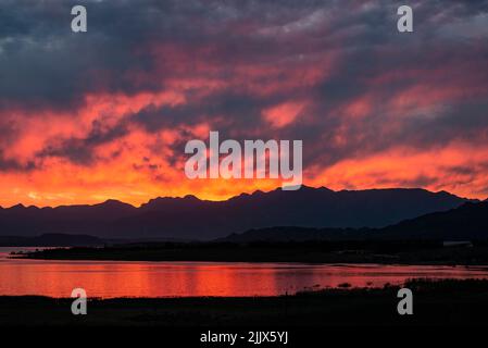 cielo di fuoco rosso su un lago in una giornata nuvolosa Foto Stock