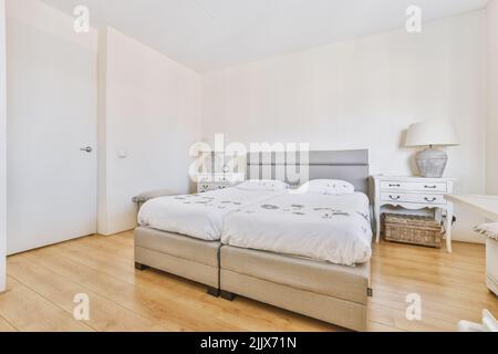 Letto comodo accanto a una porta e pavimento in legno Foto Stock