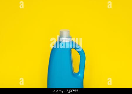 Flacone in plastica blu con tappo grigio isolato su sfondo giallo per detersivo liquido per bucato o detergente. Modello di imballaggio. Foto Stock