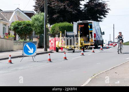 Un team BT Openreach lavora per aggiornare i residenti alla banda larga ad alta velocità sostituendo i cavi esistenti dopo aver sezionato una strada al traffico Foto Stock