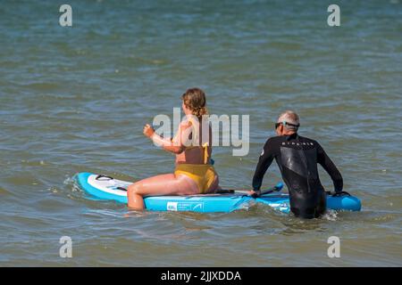 Paddleboarding, due pedalate ricreative che entrano in acqua con paddleboard lungo la costa del Mare del Nord Foto Stock