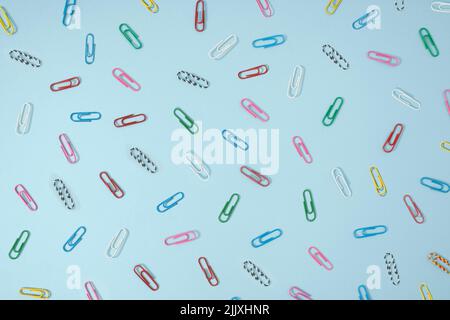 Concetto creativo di ufficio di clip di carta multicolore su sfondo blu pastello. Foto Stock