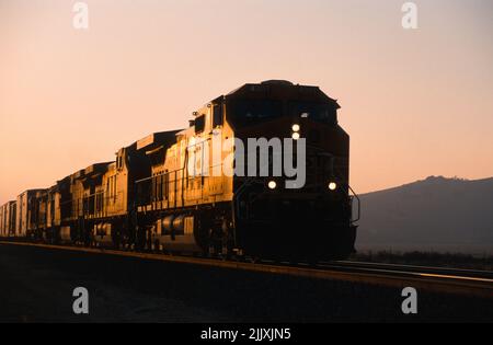 Il treno merci BNSF si dirige verso est attraverso Tehachapi al tramonto Foto Stock